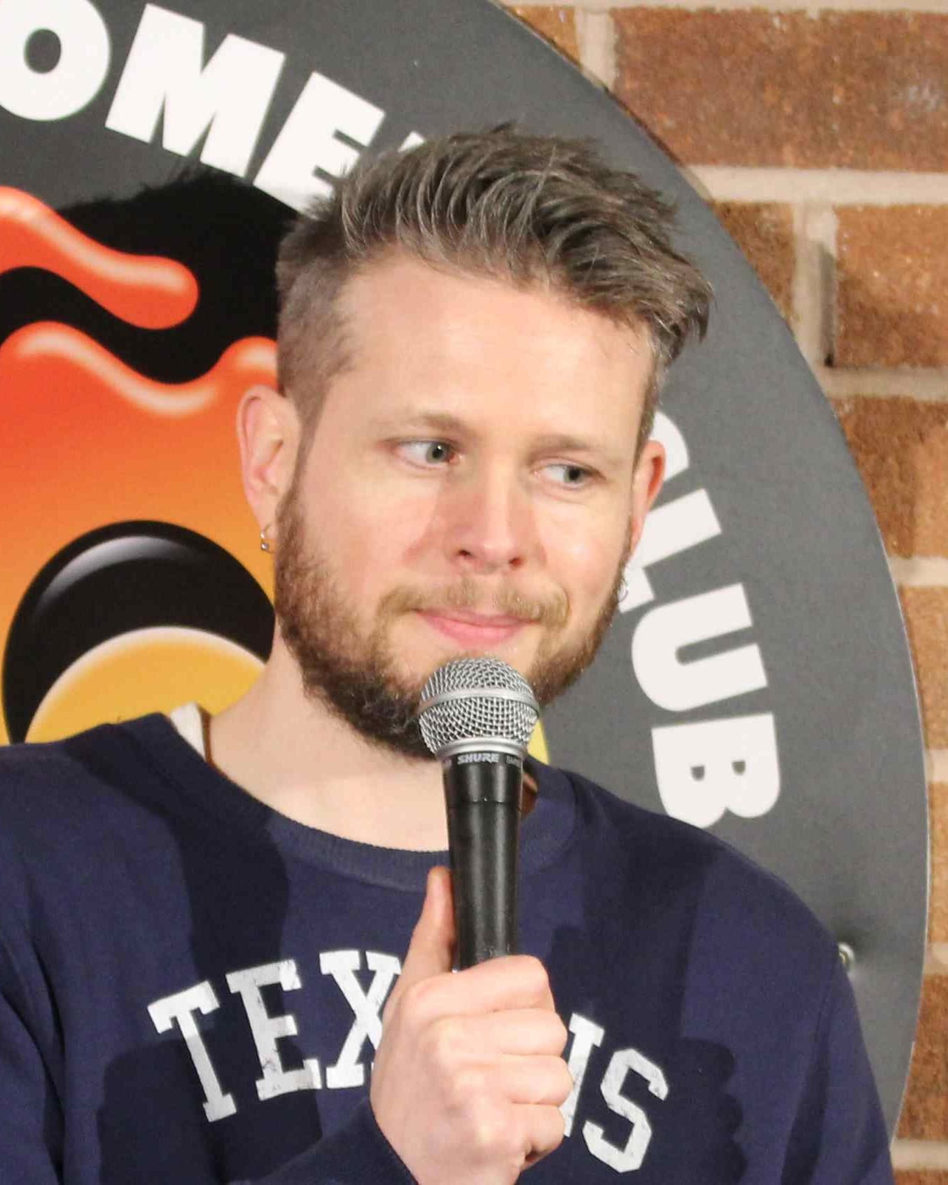 Phil Chapman on stage at Hot Water Comedy Club, giving the audience a sideways look